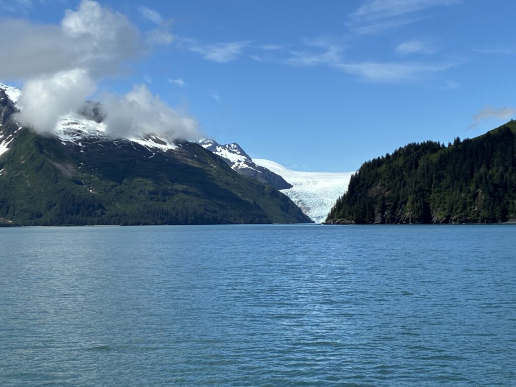 Glacial inlet with dramatic mountain peaks under blue skies, Alaska
