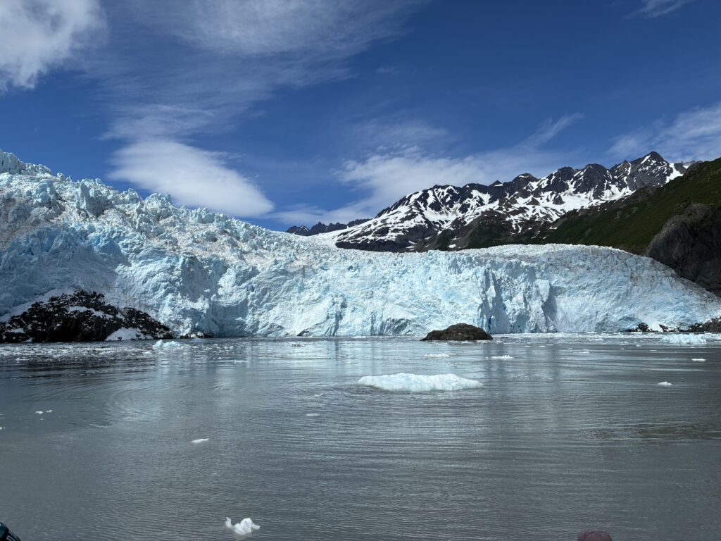 Aialik Snow-capped glacier surrounded by blue water and steep mountain cliffs