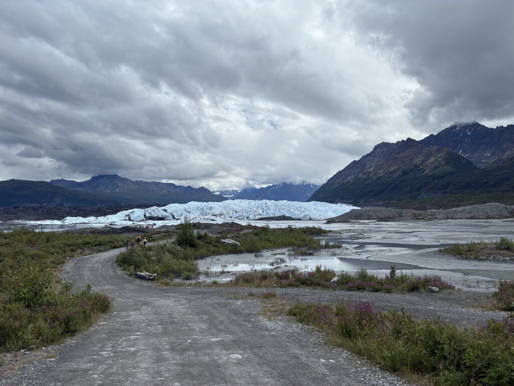 Dirt path leading toward the icy Matanuska Glacier beneath cloudy skies